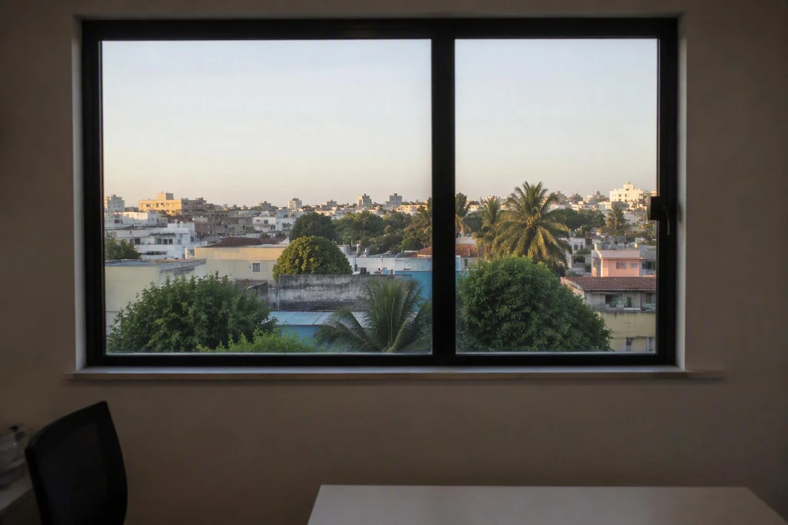 Janela do escritório com a cidade ao fundo no começo da manhã